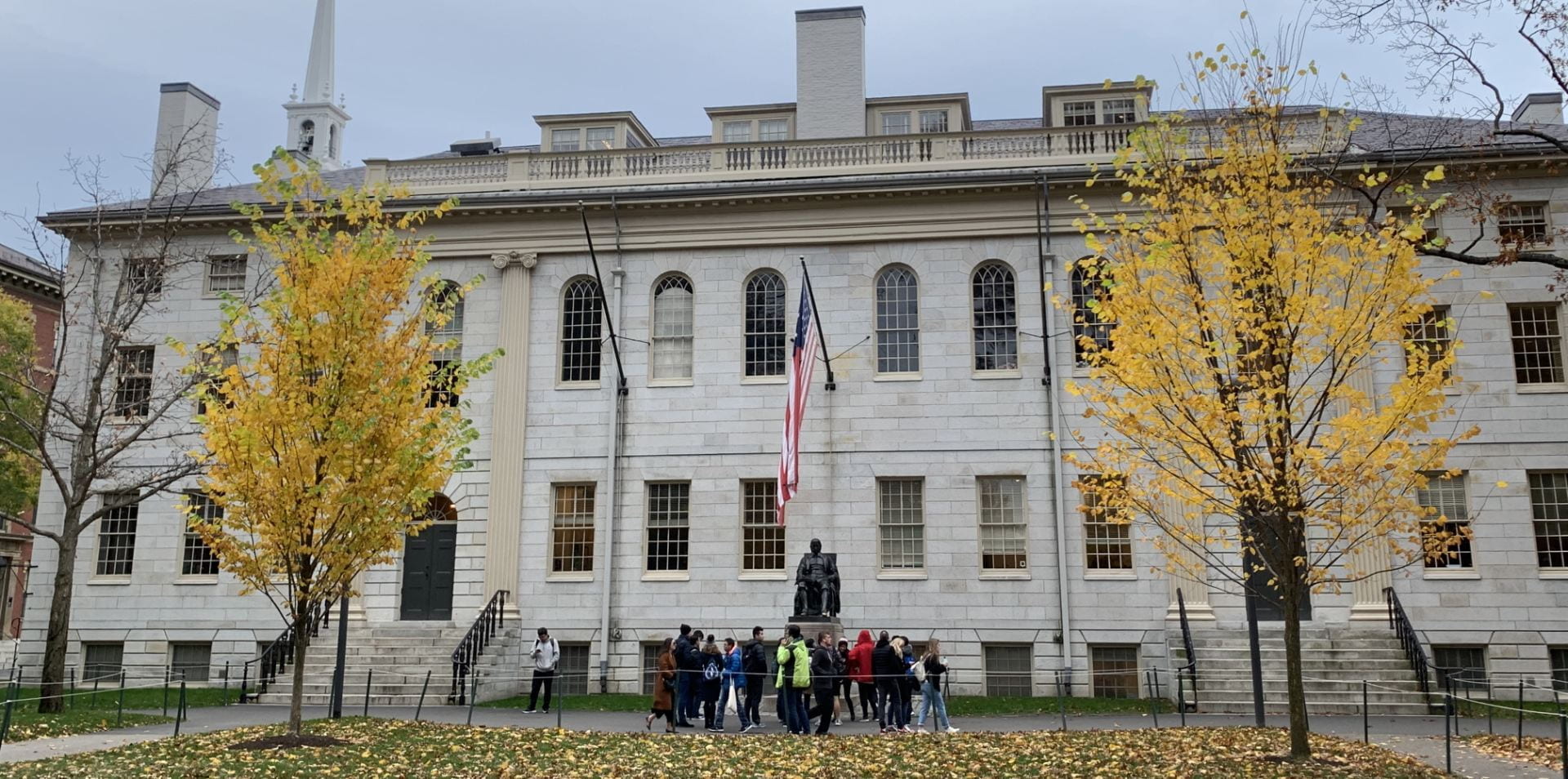 University Hall with people clustered around John Harvard statue